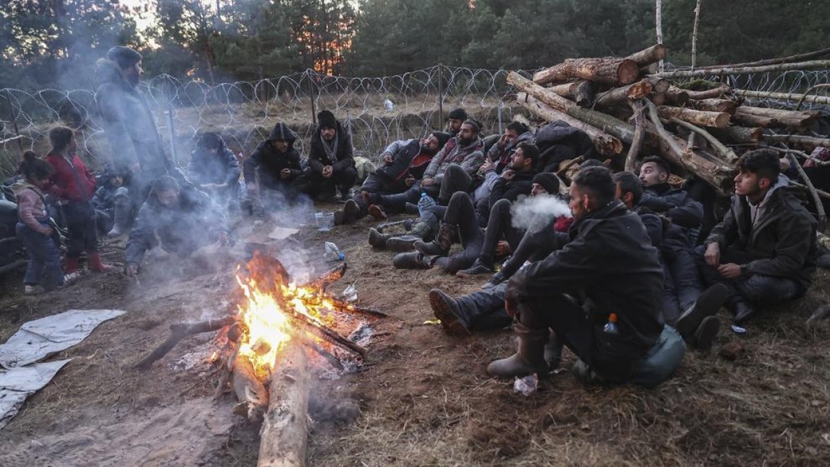 Un grupo de migrantes espera alrededor de una hoguera una oportunidad para cruzar a Polonia.