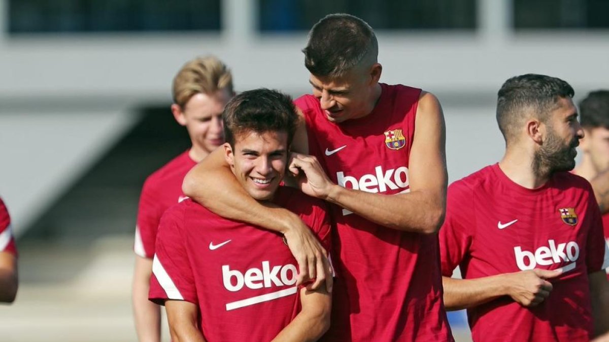 Gerard Piqué fa broma amb Riqui Puig durant l’entrenament blaugrana de divendres.