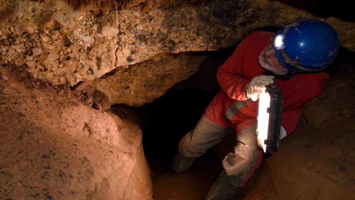 Un arqueólogo en busca de grabados rupestres en la cueva de la Font Major de L’Espluga de Francolí.