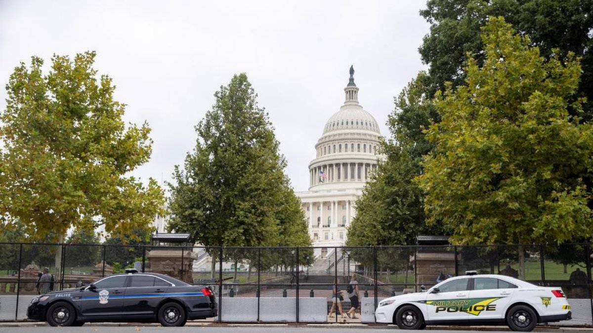 El Capitolio, rodeado con una valla negra y con coches de policía.