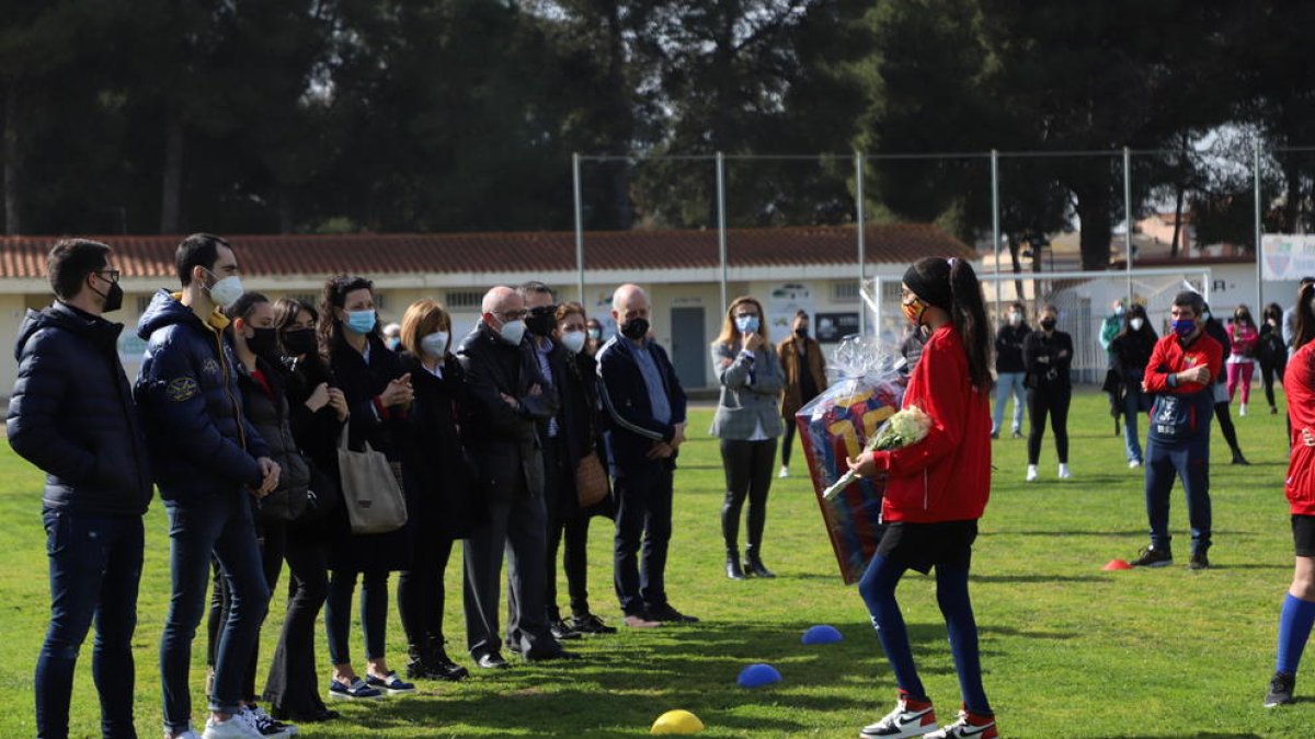 Una jugadora del Soses Femení entrega a la familia una camiseta firmada por toda la plantilla y un ramo de flores.