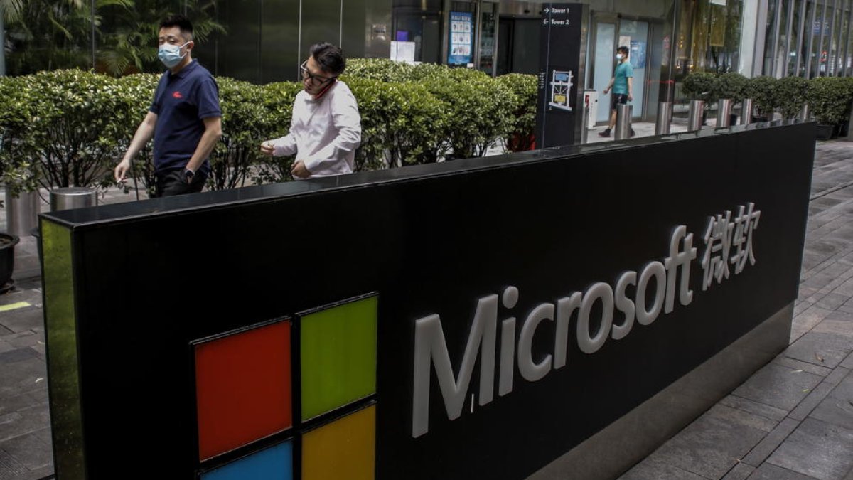 La gent passa al costat del logotip de l'empresa en un edifici d'oficines de Microsoft a Beijing, Xina