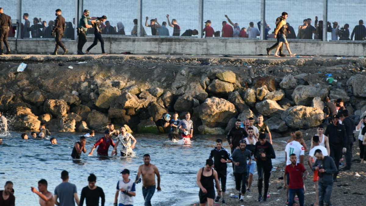 Persones migrants caminen per la platja del Tarajal, a Ceuta