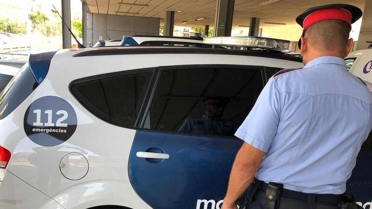 Imagen de archivo de un mossos junto a un vehículo policial.