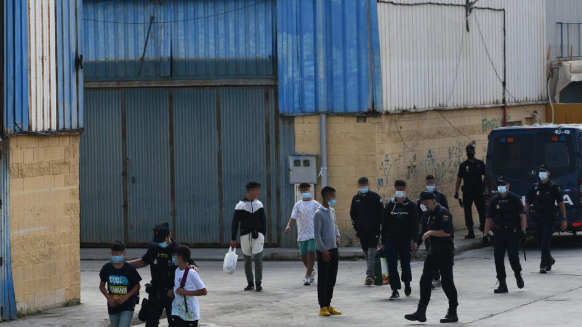 Agents de la policia de Ceuta acompanyen menors a les naus habilitades per a la seua acollida.