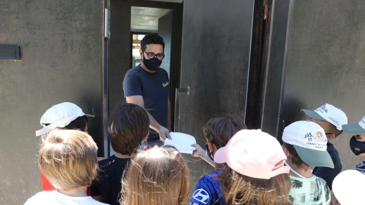 Un grupo de niños entrega una bolsa de tela a un vecino, ayer.