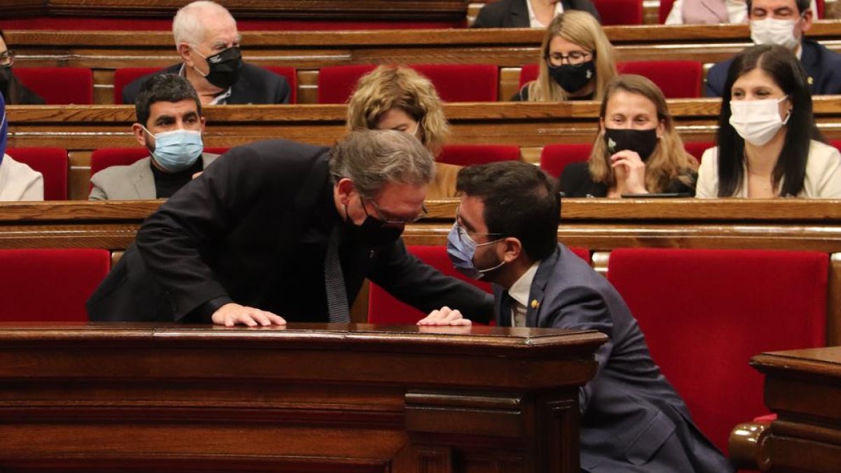 El conseller d'Economia, Jaume Giró, parlant amb el president del Govern, Pere Aragonès, durant un ple del Parlament.