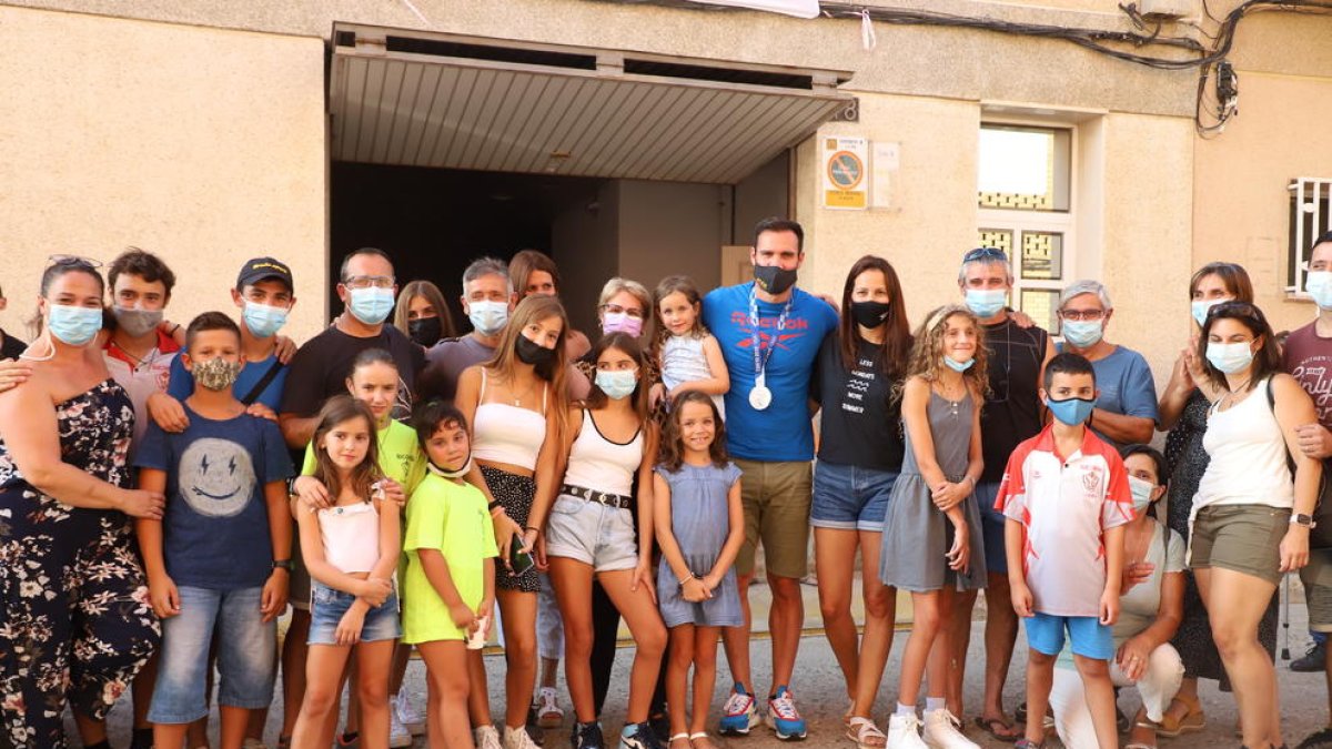 Saúl posa ante la puerta de su casa junto a su familiares, amigos y vecinos que se reunieron para darle la bienvenida.