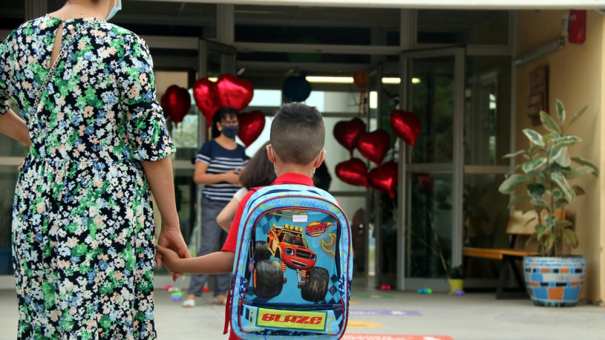 Imagen de un niño llegando a clase de la mano de su madre.