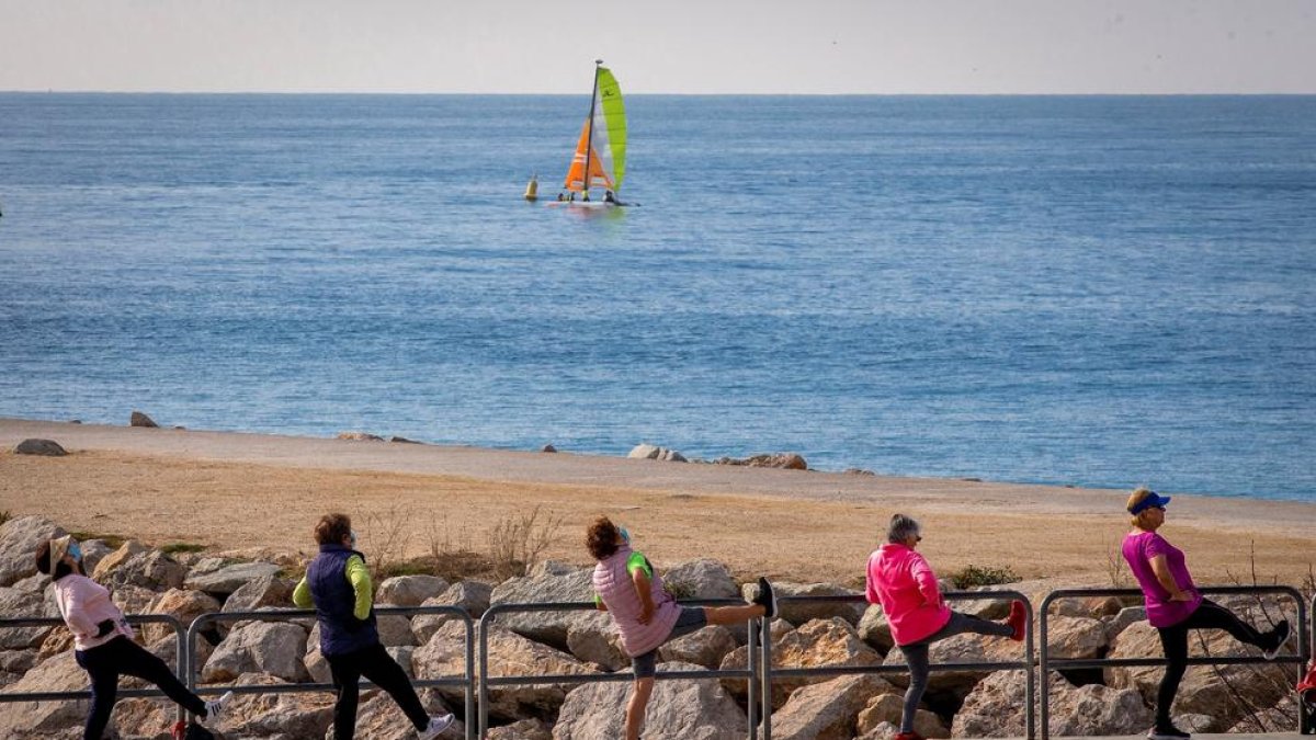 Varias personas hacen ejercicio en la playa barcelonesa de Nova Icaria.