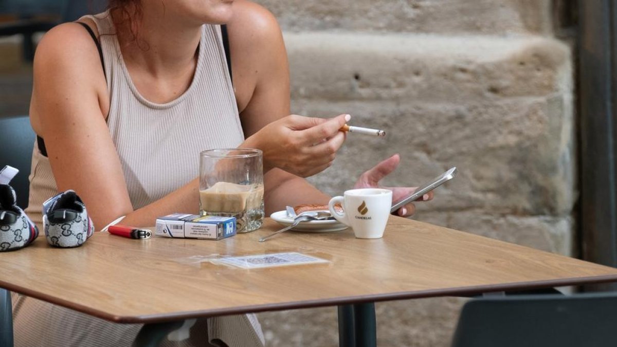 Una mujer fuma un cigarrillo en una terraza