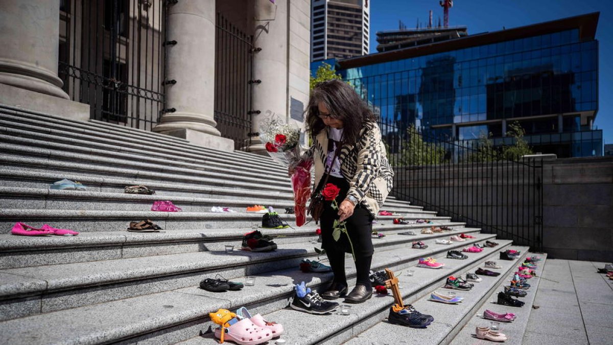 Una nativa coloca rosas en homenaje a los 215 niños cuyos restos fueron hallados estos días.