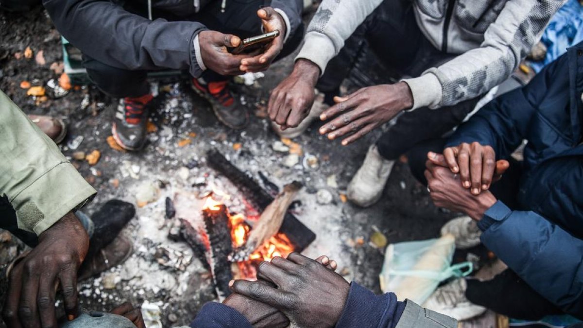 Un grupo de migrantes se calienta en un campamento en Calais.