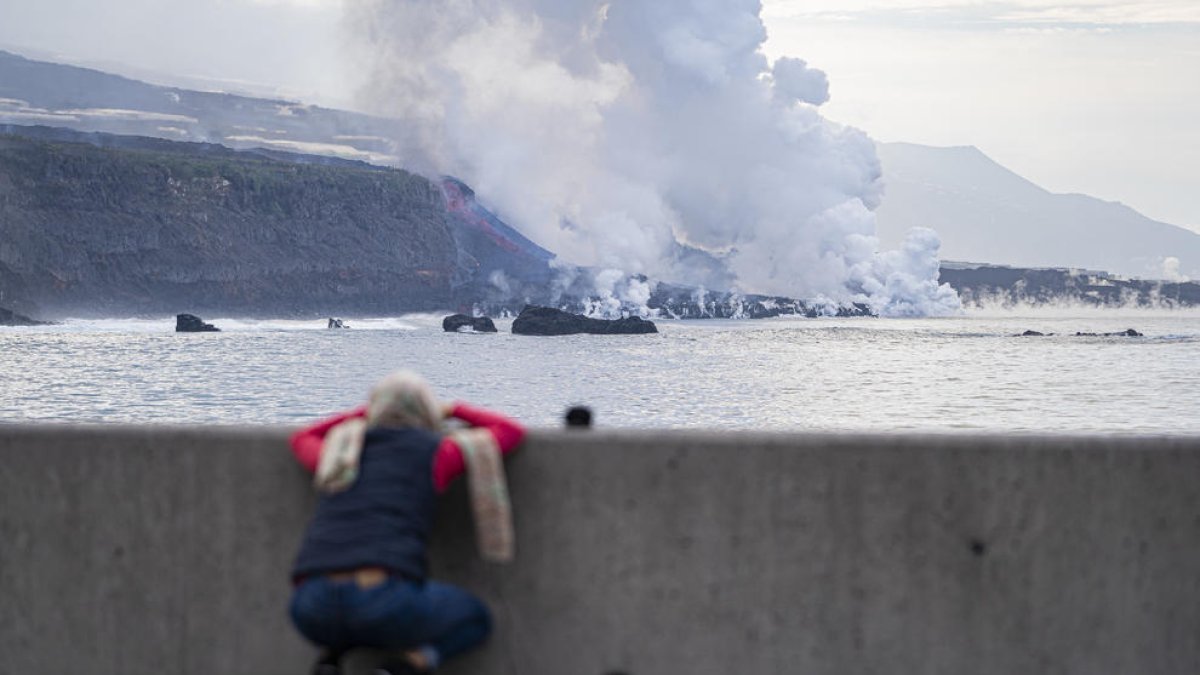 Una persona observa els ramals de lava a l’arribada al mar.