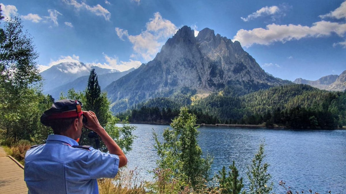 Un agente de la URMA de los Mossos haciendo vigilancia en Aigüestortes en el lago de Sant Maurici, con Els Encantats al fondo. 