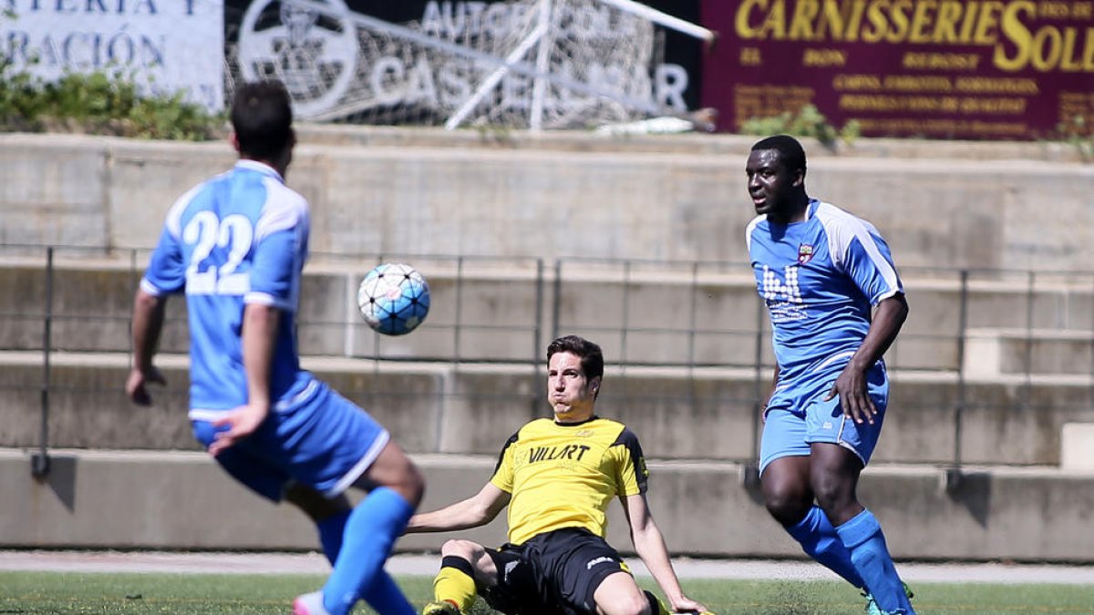 Un jugador del Balaguer despeja un balón ante la proximidad de dos jugadores rivales.