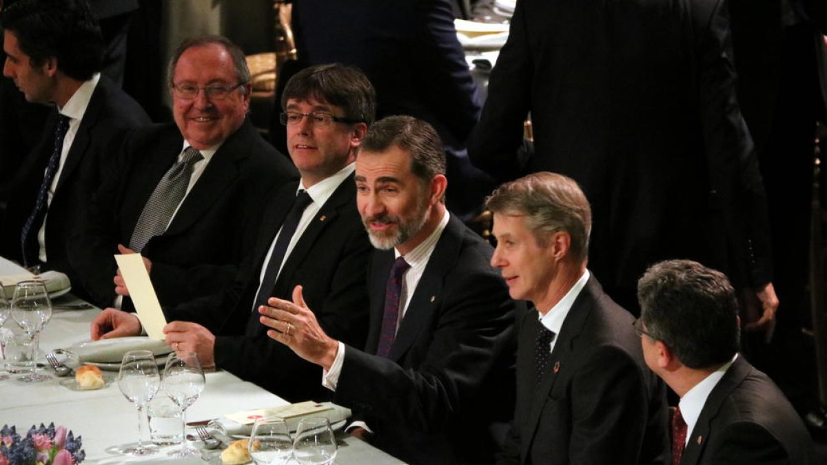 Felipe VI y Carles Puigdemont conversan con comensales en la mesa presidencial en la cena de bienvenida del MWC 2017.