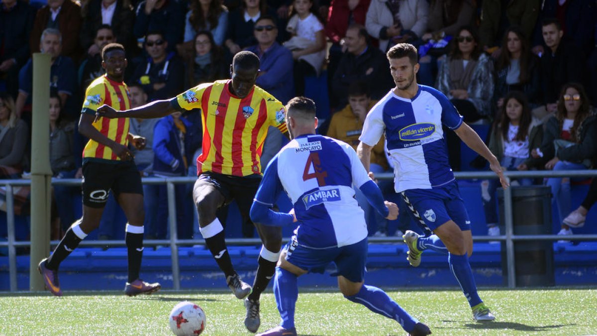 Moustapha, autor del gol del Lleida, intenta superar Pajarero, en una acció del partit d’ahir, mentre el seu company Mousa l’observa.