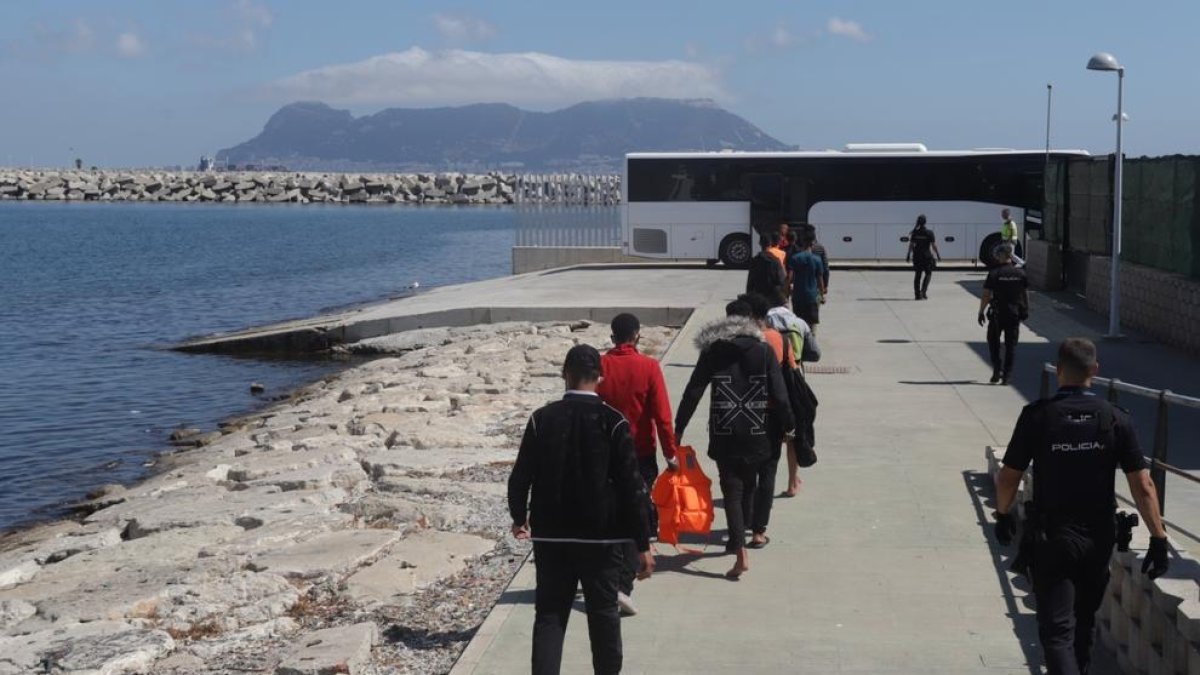 Inmigrantes, acompañados de la policía nacional, caminan hacia un autobús durante el rescate de 31 magrebíes, diez menores, de una patera el 23 de septiembre de 2022 en Cádiz.