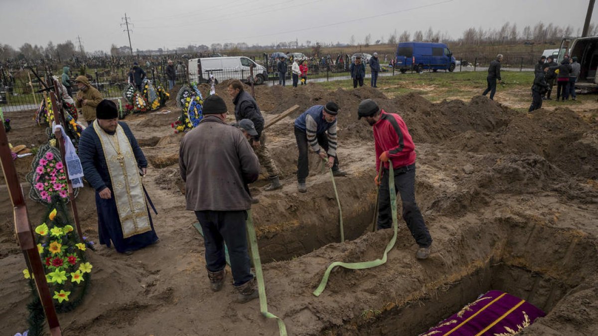 Varias personas entierran un cuerpo en el cementerio de Bucha, cerca de Kiev.