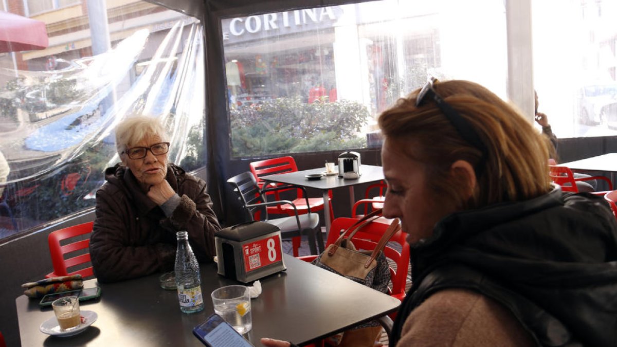 Una dona consulta el missatge de Protecció Civil a la terrassa d’un bar a la Pobla de Segur.