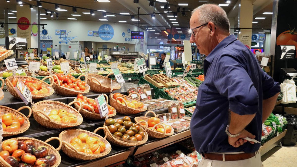 Un hombre observa los precios de los tomates en un supermercado. 