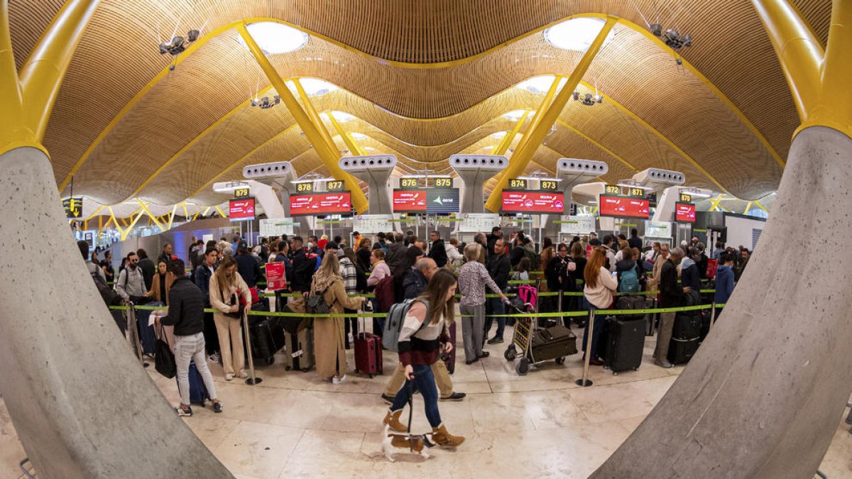 Passatgers preparant-se per embarcar a Barajas dissabte.