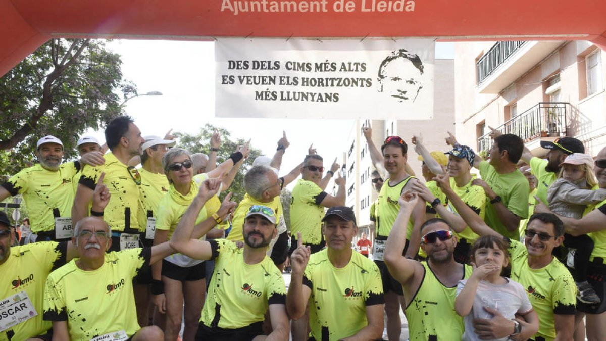 Unos corredores señalan la pancarta bajo el arco de salida y llegada recordando la figura de Garra.