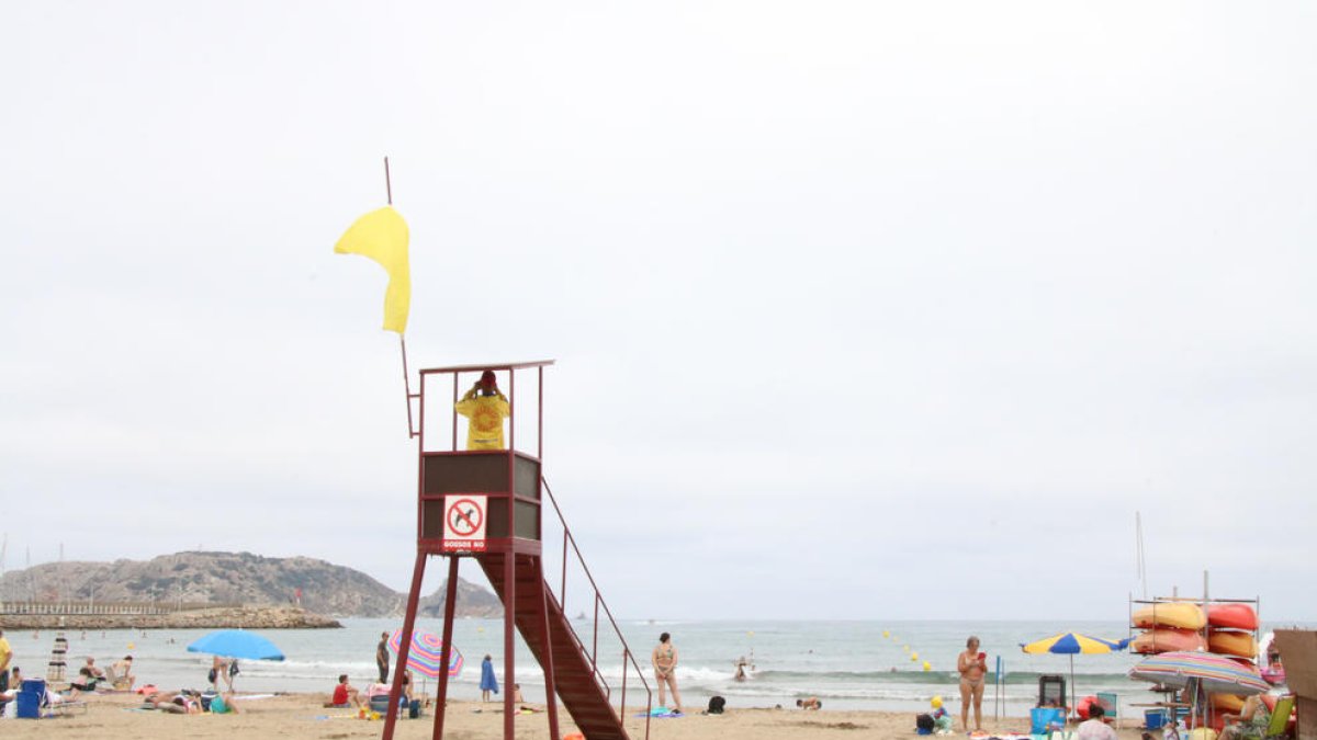 Un socorrista, junto a la bandera amarilla, en una playa de Catalunya.