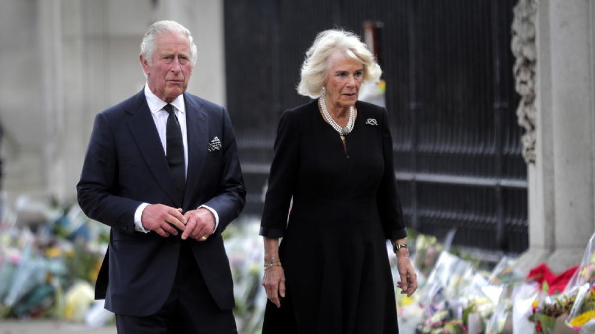 El rey Carlos III y Camila, la reina consorte, miran los tributos florales dejados fuera del Palacio de Buckingham este viernes.