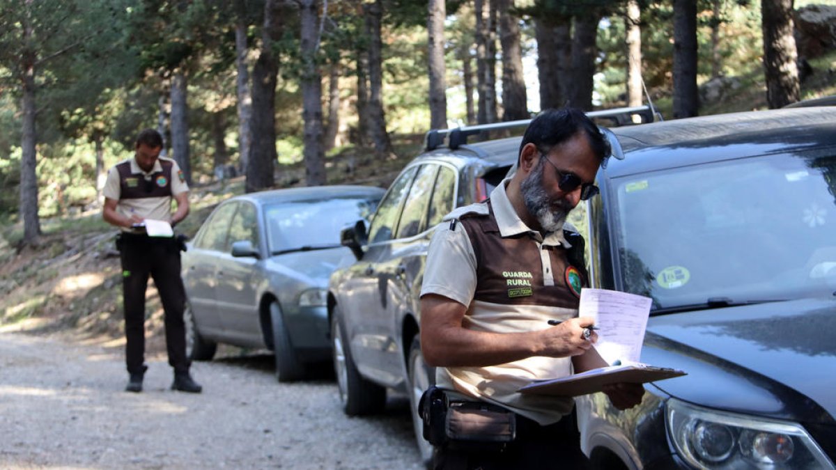 Una pareja de guardas rurales multando varios vehículos a una pista forestal de Riu de Cerdanya