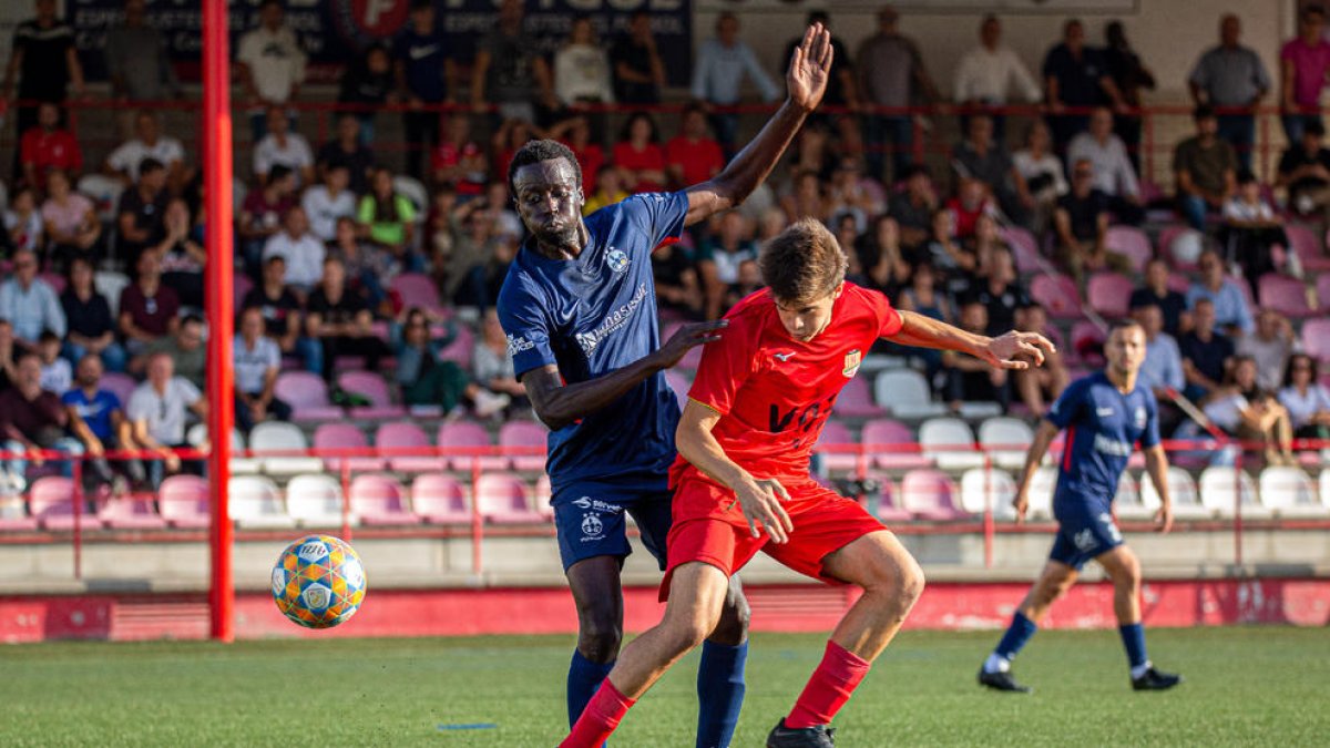 Abdoulaye Fall lluita la pilota amb un jugador de la Pirinaica durant el partit.