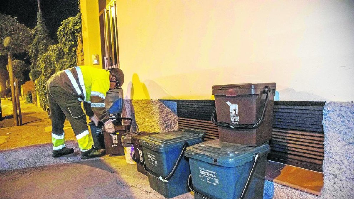 Un operari recollint les escombraries dels cubells que es deixen a la nit en un dels carrers d'Arbeca.