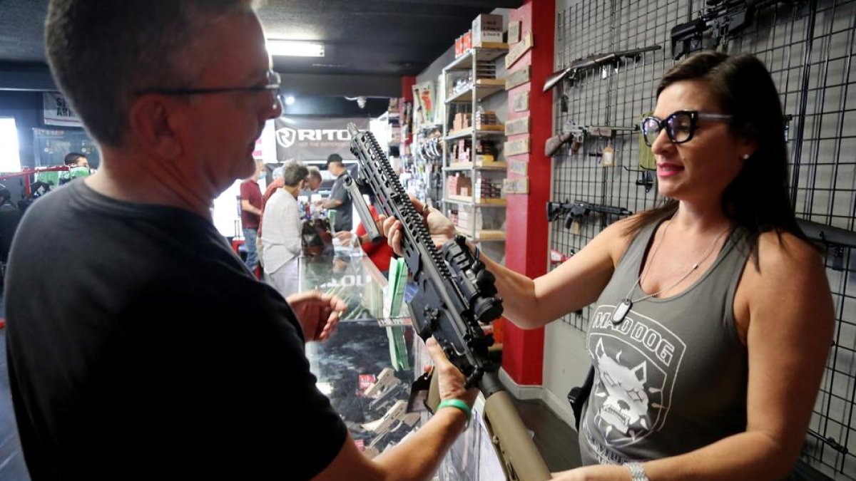 Un home observa un fusell en una botiga d'armes en Florida.
