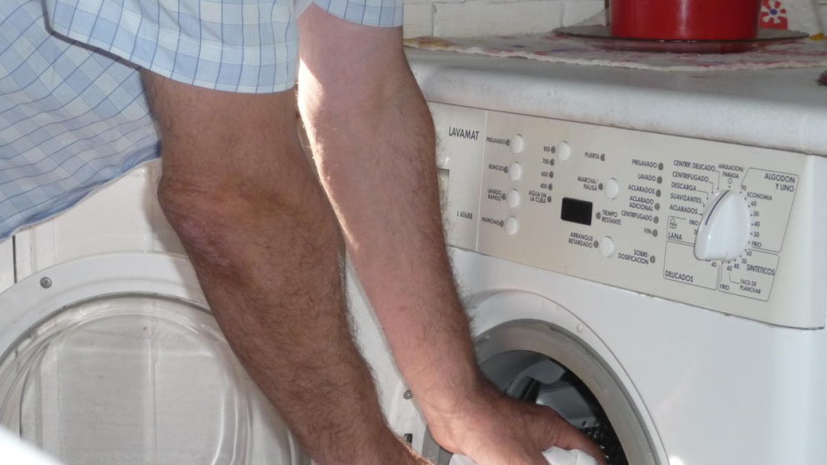 Un home introdueix roba en una rentadora domèstica.