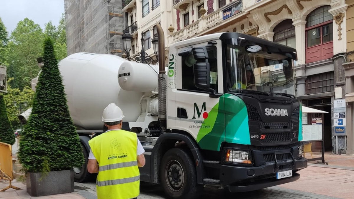 Un treballador de la construcció ajuda a maniobrar un company que condueix un camió.