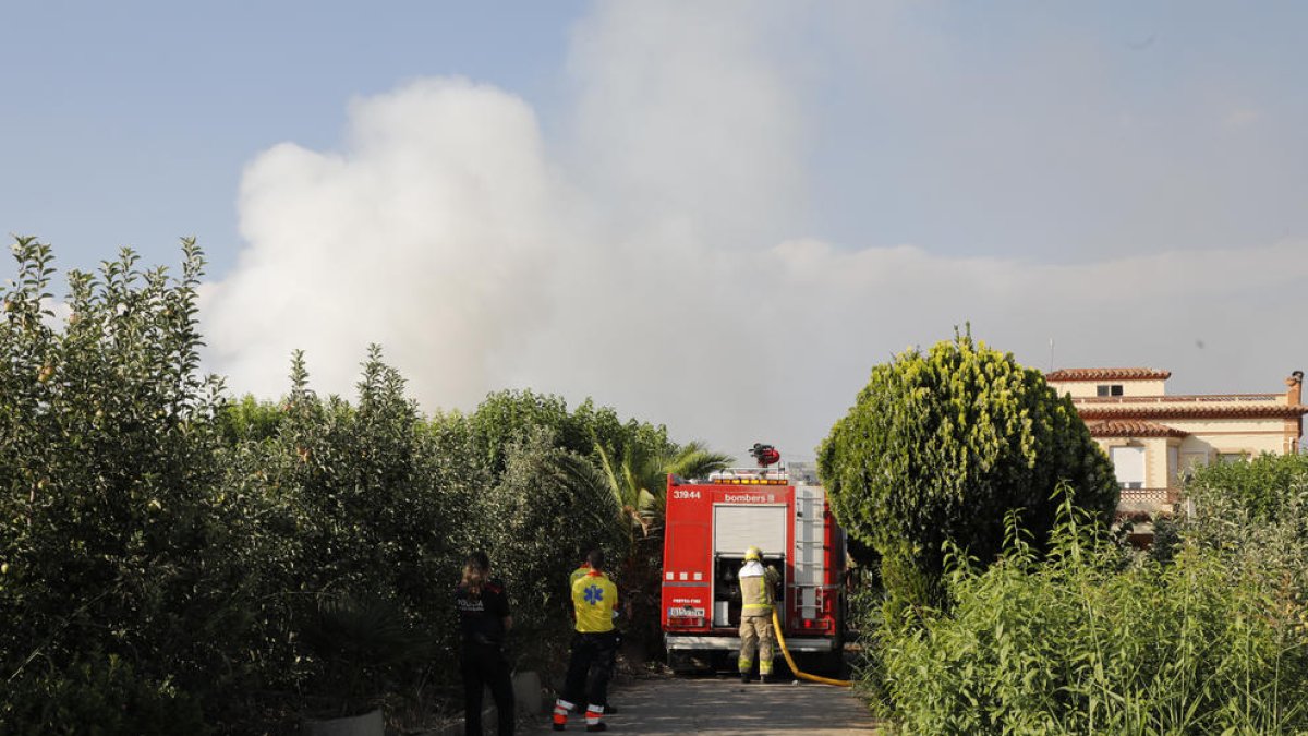 Imatge de la columna de fum (esquerra) i de dos bombers treballant en l’extinció del foc (dreta).