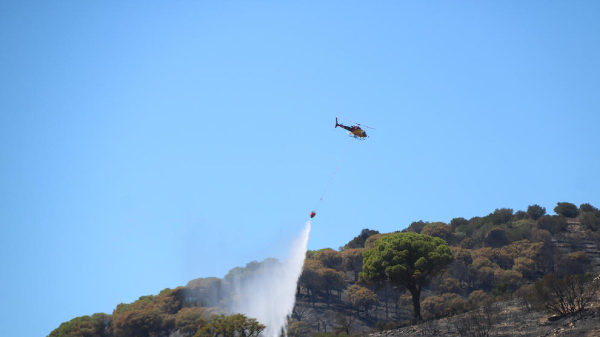 Un helicòpter descarrega aigua sobre un dels focus registrats a Portbou.