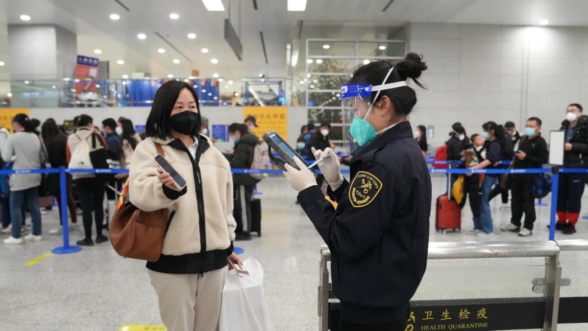 Un trabajador del aeropuerto de Pekín revisa la documentación de una viajera el pasado domingo. 