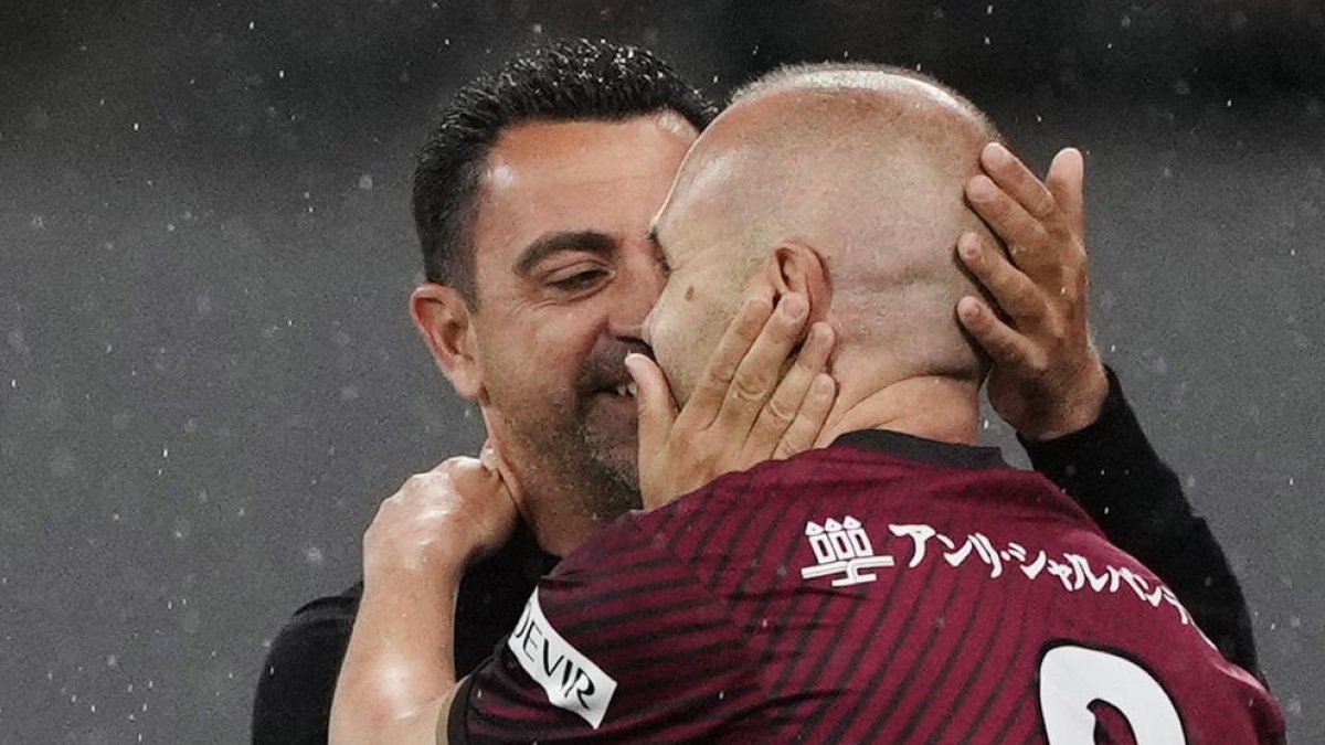 Xavi e Iniesta se abrazan durante el partido de ayer.