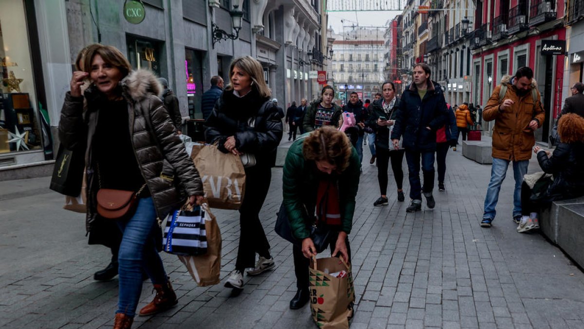 Varias personas caminan con bolsas de las rebajas en la calle Preciados de Madrid.