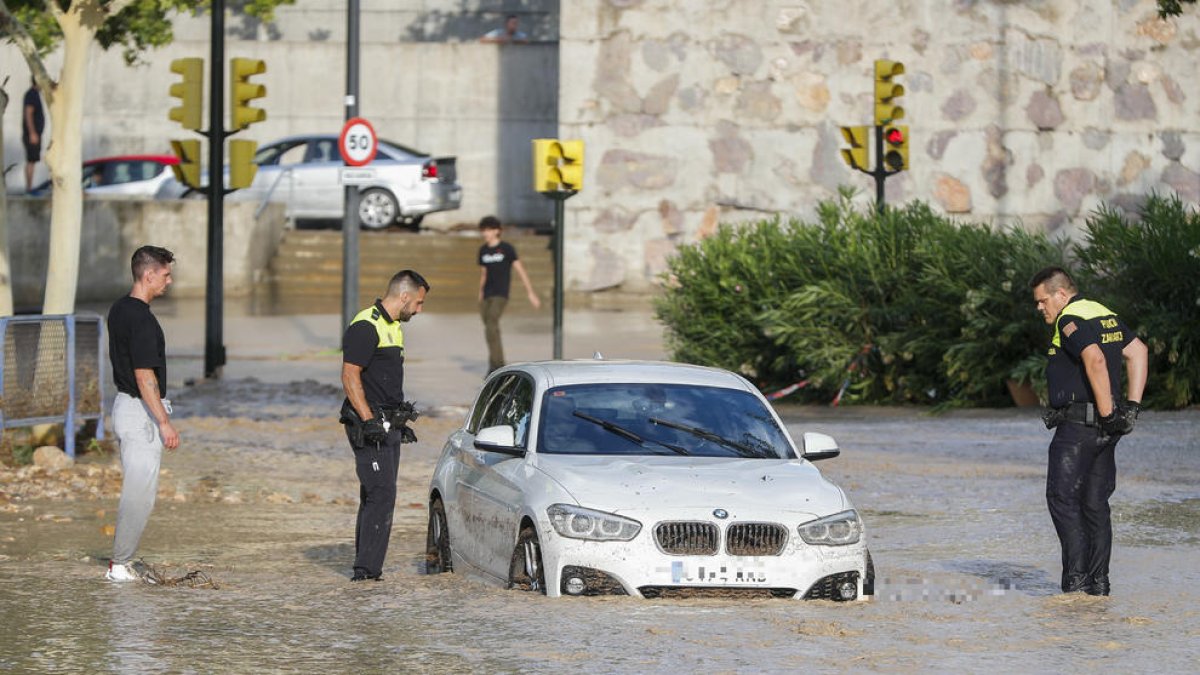 AgAgentes de la Policía Local observan un coche arrastrado por la tormenta caída este jueves en Zaragoza.entes de la Policía Local observan un coche arrastrado por la tormenta caída este jueves en Zaragoza.