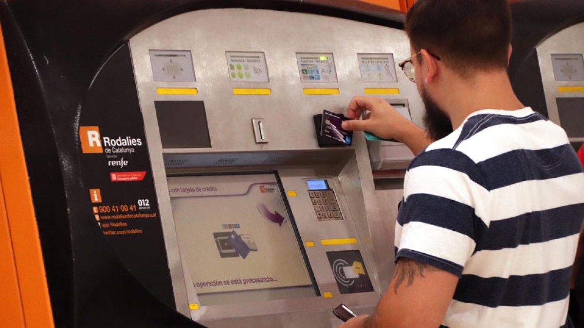 Un chico utilizando una máquina de autoventa de Rodalies el primer día en vigor de los abonos gratuitos.