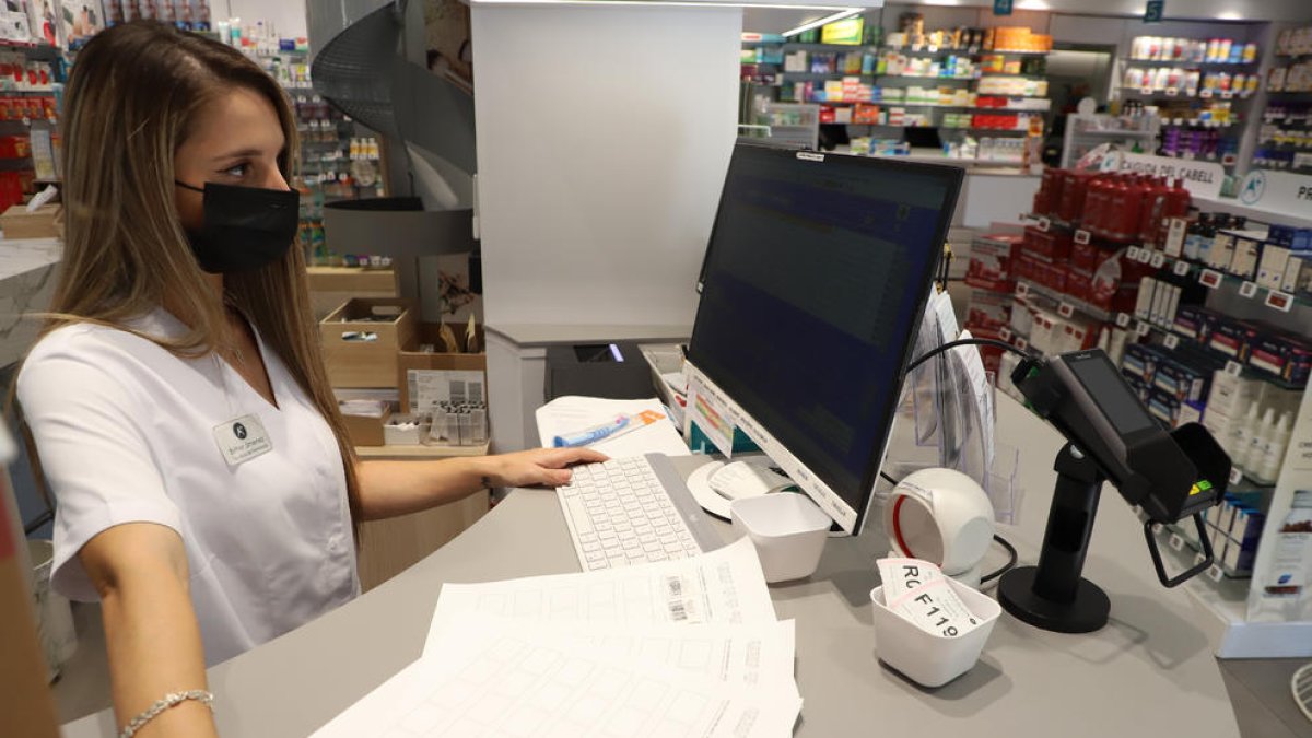 Una farmacéutica de Lleida ciudad intentando sin éxito dispensar un medicamento.