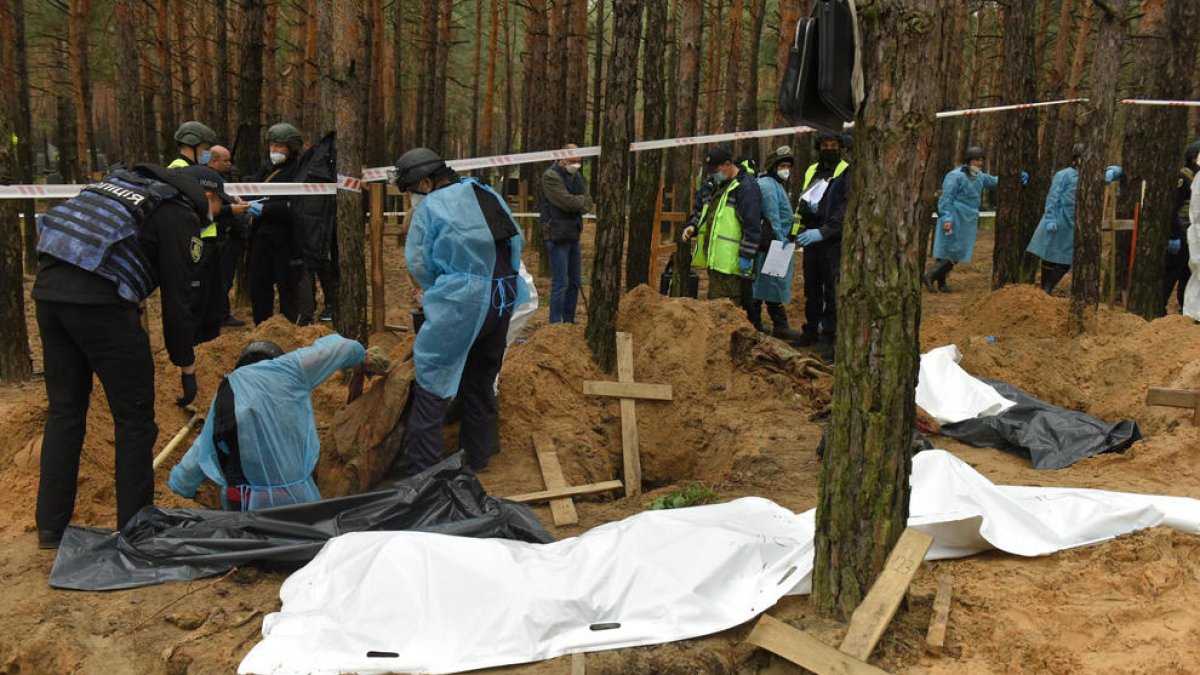 Trabajadores exhumando los cuerpos en la fosa común hallada en la ciudad de Izium.