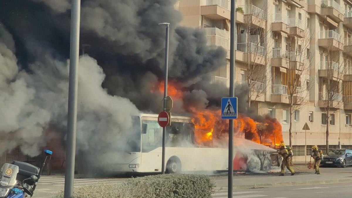 Els bombers proven de sufocar les flames de l’autobús.