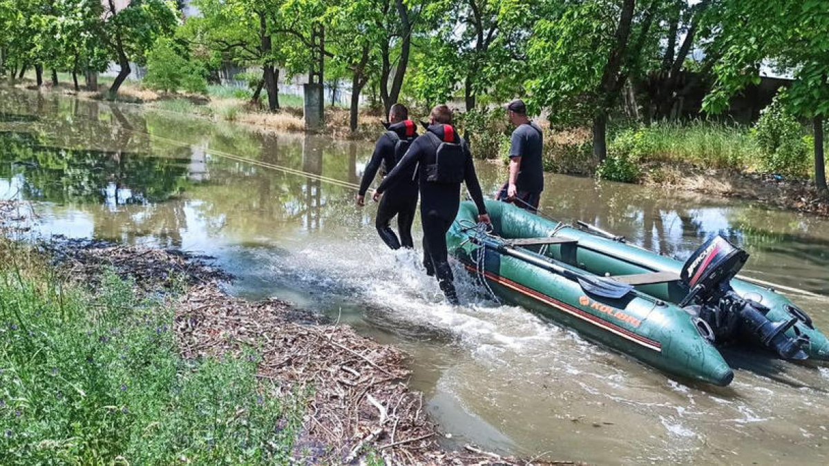 Rescatistas ucranianos arrastran un bote para evacuar a civiles atrapados por la inundación.