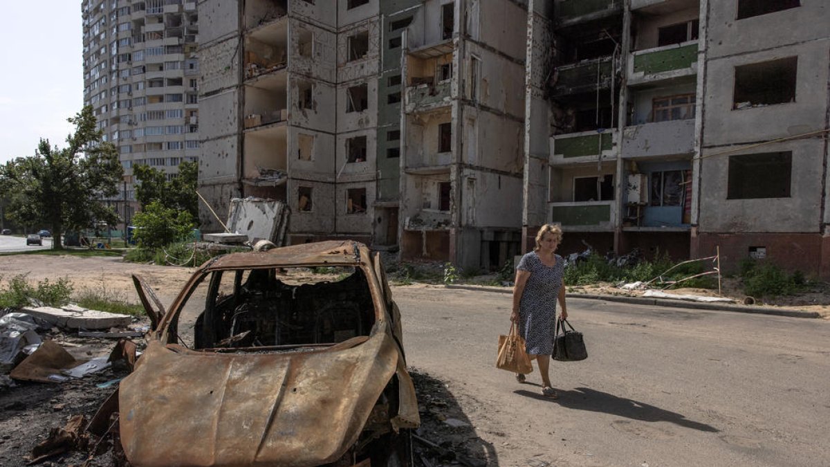 Una dona passant ahir dilluns pel costat d’un cotxe cremat a Txerníhiv, al nord d’Ucraïna.