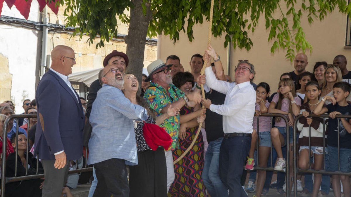 El conseller Giró, a la derecha con camisa, participando en el concurso para subir sacos con polea.