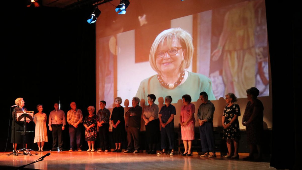 La compañía teatral de Mequinensa ante una foto de la alcaldesa fallecida, Magda Godia.